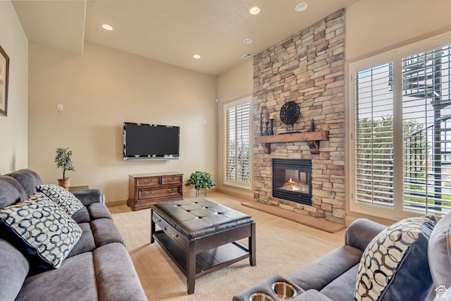 carpeted living area featuring a stone fireplace, baseboards, and recessed lighting