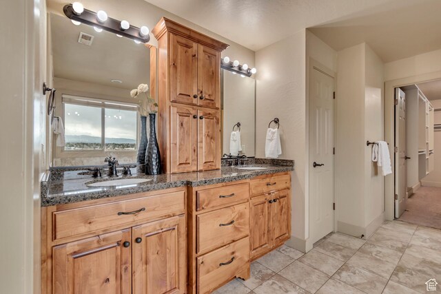 bathroom with double vanity, visible vents, baseboards, and a sink