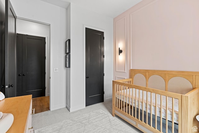 bedroom with light carpet and a nursery area