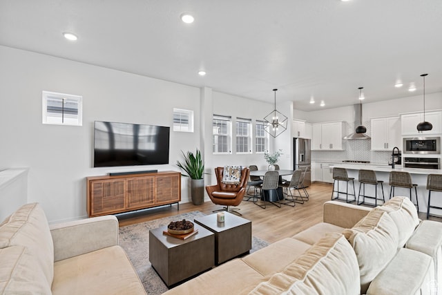 living room featuring a wealth of natural light, a notable chandelier, light wood-style floors, and recessed lighting