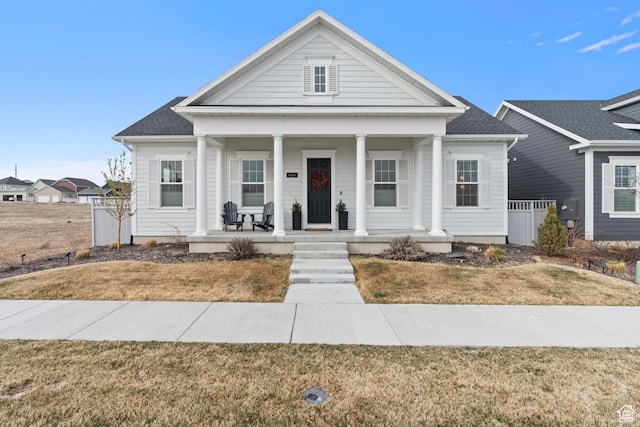 greek revival inspired property with covered porch, fence, and roof with shingles