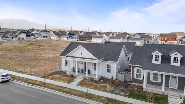 view of front of home with covered porch, a shingled roof, and a residential view