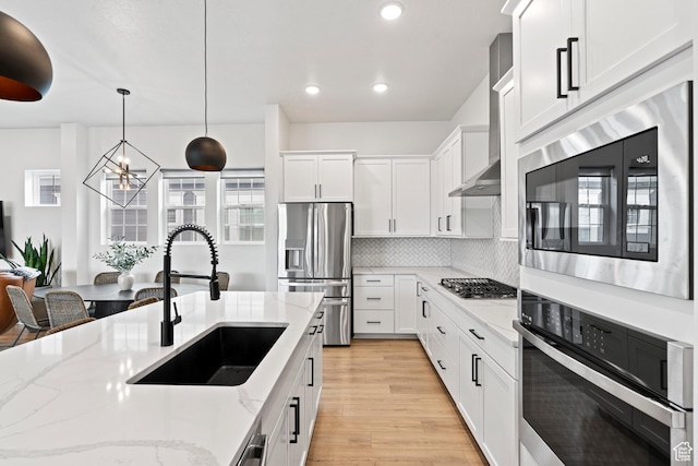kitchen with decorative backsplash, white cabinets, stainless steel appliances, a sink, and an inviting chandelier