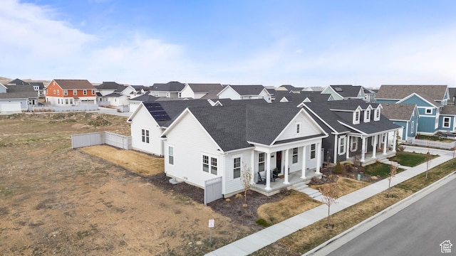 exterior space with a residential view, covered porch, fence, and roof with shingles