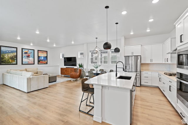 kitchen featuring open floor plan, stainless steel appliances, a breakfast bar, a center island with sink, and a sink