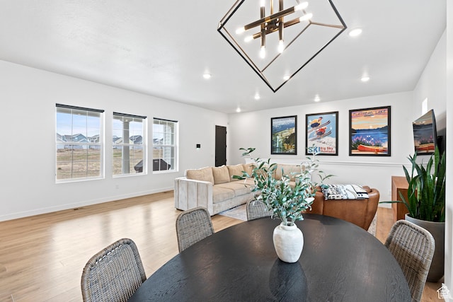 dining room featuring baseboards, recessed lighting, light wood-style floors, and a notable chandelier