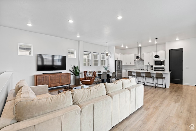living area with light wood-style floors, recessed lighting, and an inviting chandelier