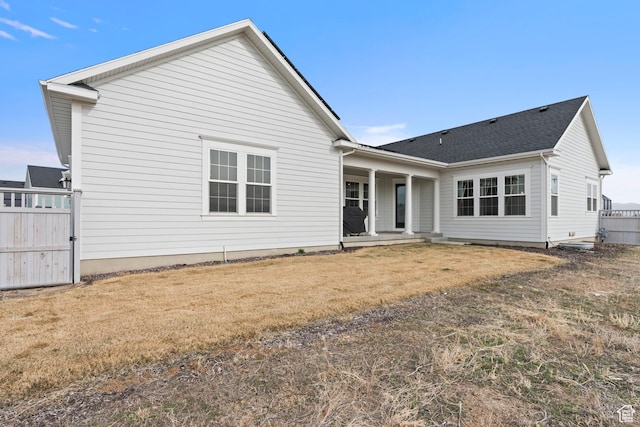 back of property featuring fence and a yard