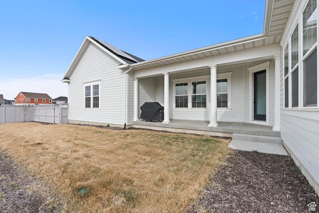 exterior space featuring a porch, fence, and a lawn