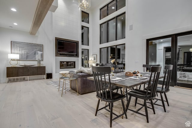 dining space with beamed ceiling, wood finished floors, recessed lighting, a high ceiling, and a notable chandelier