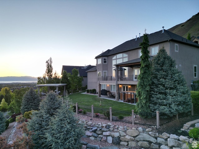 2524 E 700 S, Springville, UT 84663 - back of property at dusk with a balcony, stucco siding, a patio, and a yard