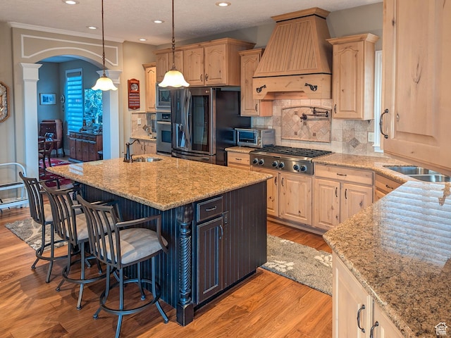 2524 E 700 S, Springville, UT 84663 - kitchen with a breakfast bar area, premium range hood, a sink, light wood finished floors, and appliances with stainless steel finishes