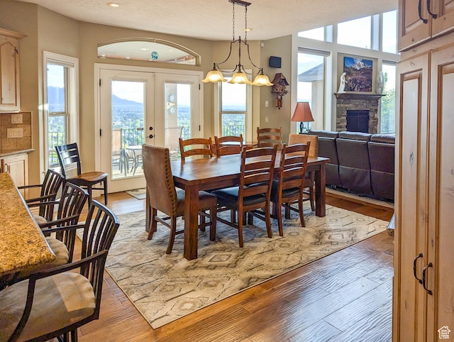 2524 E 700 S, Springville, UT 84663 - dining space with a stone fireplace, light wood-style floors, french doors, and a textured ceiling