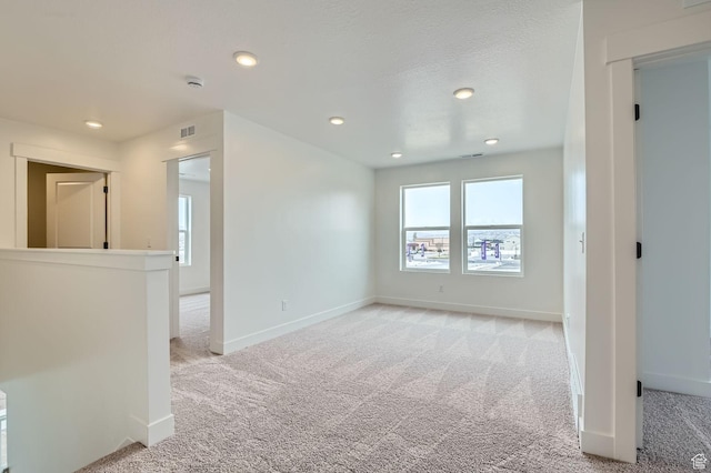 empty room with light carpet, recessed lighting, and baseboards