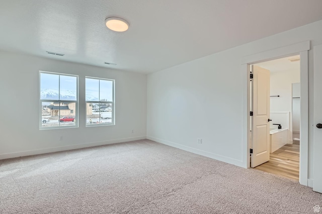 empty room with visible vents, baseboards, light colored carpet, and a textured ceiling