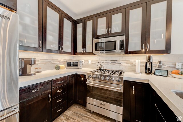 3676 Blackstone Dr, Park City, UT 84098 - kitchen featuring light countertops, tasteful backsplash, light wood-style flooring, dark brown cabinetry, and appliances with stainless steel finishes
