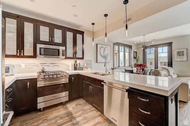 3676 Blackstone Dr, Park City, UT 84098 - kitchen with stainless steel appliances, a chandelier, backsplash, a sink, and a peninsula
