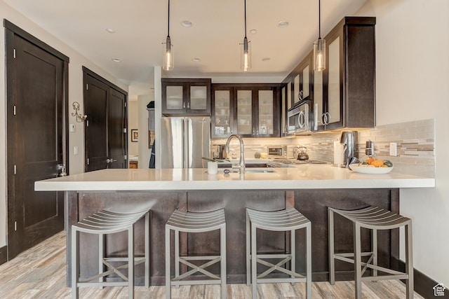 3676 Blackstone Dr, Park City, UT 84098 - kitchen featuring tasteful backsplash, a sink, a peninsula, appliances with stainless steel finishes, and glass insert cabinets