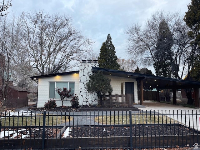 view of front of home with driveway, brick siding, a fenced front yard, and a carport