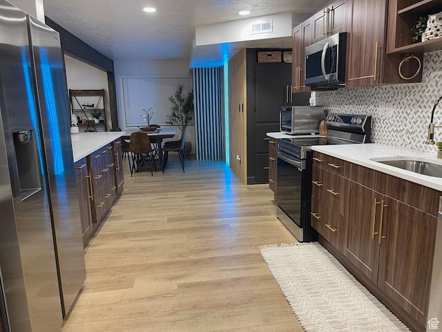 3444 S 1100 E, Millcreek, UT 84106 - kitchen featuring light countertops, stainless steel appliances, decorative backsplash, a sink, and light wood-style flooring