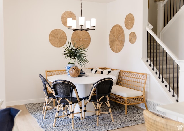 dining space featuring visible vents, a chandelier, baseboards, wood finished floors, and stairway