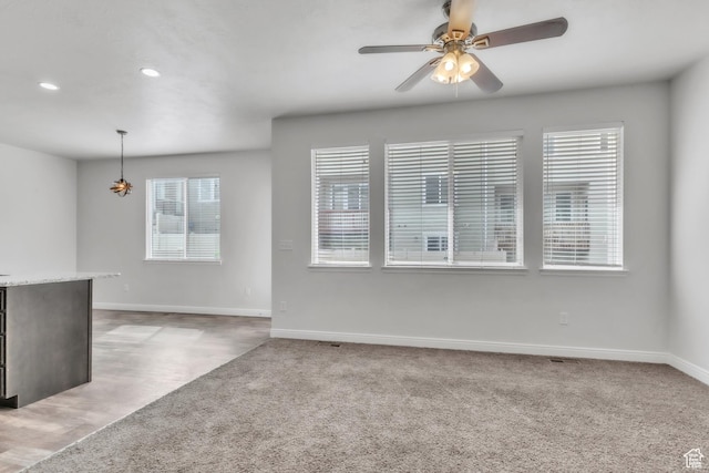 14292 S Autumn Path Ln W, Riverton, UT 84096 - unfurnished living room with a healthy amount of sunlight, baseboards, a ceiling fan, and light colored carpet