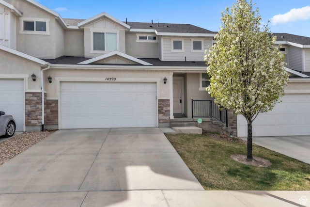 view of property with an attached garage, stucco siding, stone siding, and concrete driveway