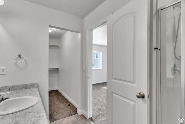 14292 S Autumn Path Ln W, Riverton, UT 84096 - full bathroom with a walk in closet, vanity, baseboards, visible vents, and a stall shower