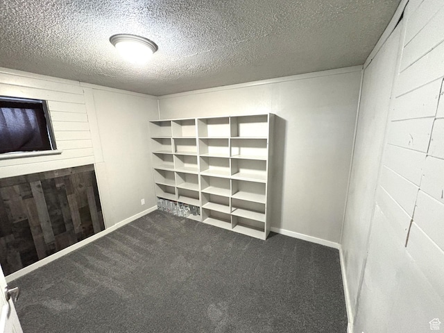 carpeted empty room with baseboards, wooden walls, and a textured ceiling