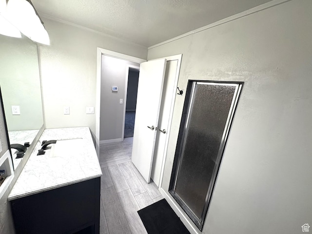 full bathroom with vanity, a textured wall, a textured ceiling, a shower stall, and wood tiled floor