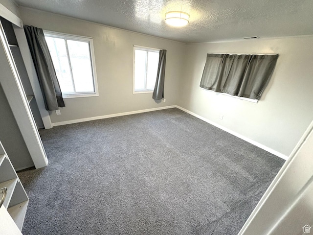 unfurnished bedroom with baseboards, a textured ceiling, and dark carpet
