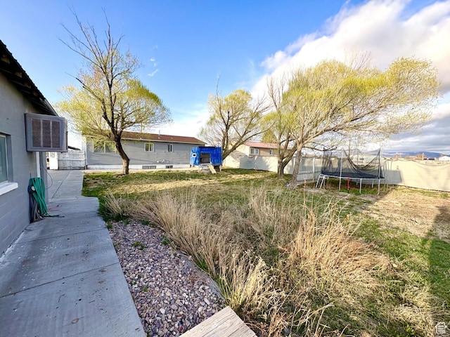 view of yard with a trampoline and fence