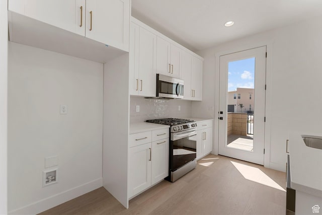 518 W Olive Ln, St George, UT 84790 - kitchen with appliances with stainless steel finishes, light wood-type flooring, tasteful backsplash, light countertops, and white cabinets