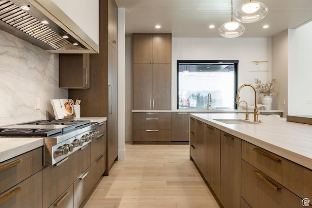 13926 S Jarvie Ln E, Draper, UT 84020 - kitchen with wall chimney exhaust hood, stainless steel gas stovetop, a sink, light wood-type flooring, and hanging light fixtures