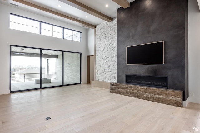 13926 S Jarvie Ln E, Draper, UT 84020 - unfurnished living room featuring beam ceiling, a high ceiling, wood finished floors, a large fireplace, and visible vents