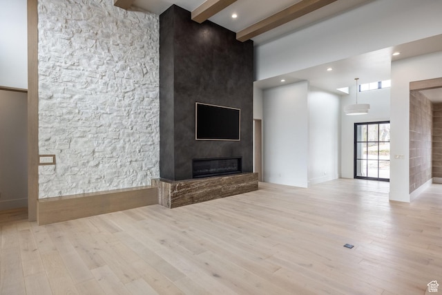 13926 S Jarvie Ln E, Draper, UT 84020 - unfurnished living room featuring a large fireplace, a towering ceiling, beam ceiling, and wood finished floors