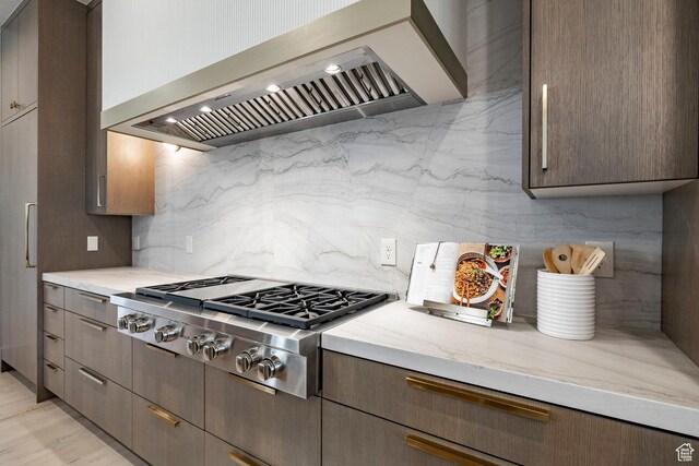 13926 S Jarvie Ln E, Draper, UT 84020 - kitchen featuring wall chimney range hood, stainless steel gas stovetop, decorative backsplash, and light stone countertops