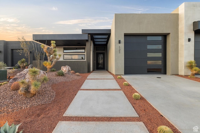 view of front of house with a garage, concrete driveway, and stucco siding