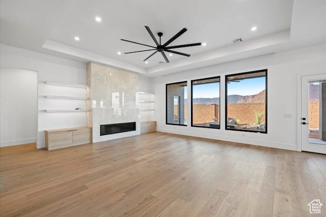121 E Terrace Ln, Ivins, UT 84738 - unfurnished living room with a fireplace, a raised ceiling, light wood-style floors, and baseboards