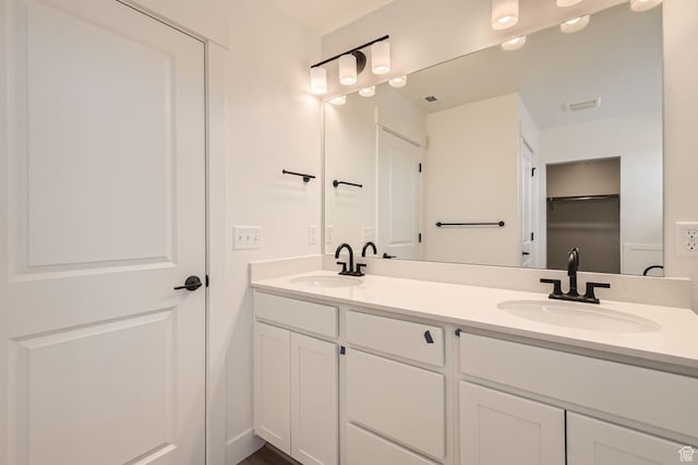 bathroom with double vanity, a sink, and visible vents