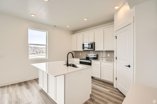 kitchen featuring tasteful backsplash, light wood-style flooring, white cabinetry, and stainless steel appliances