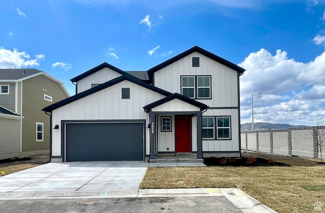 modern farmhouse featuring board and batten siding, a front yard, a garage, and concrete driveway