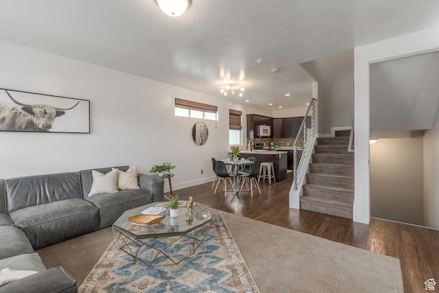 living area with stairs, baseboards, and dark wood-style flooring