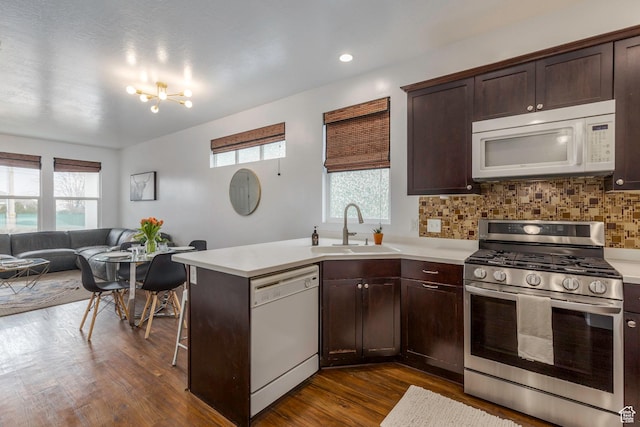 kitchen featuring light countertops, a sink, white appliances, dark wood-type flooring, and dark brown cabinets