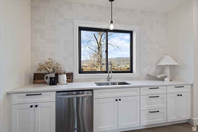kitchen featuring decorative backsplash, light countertops, white cabinetry, a sink, and stainless steel dishwasher
