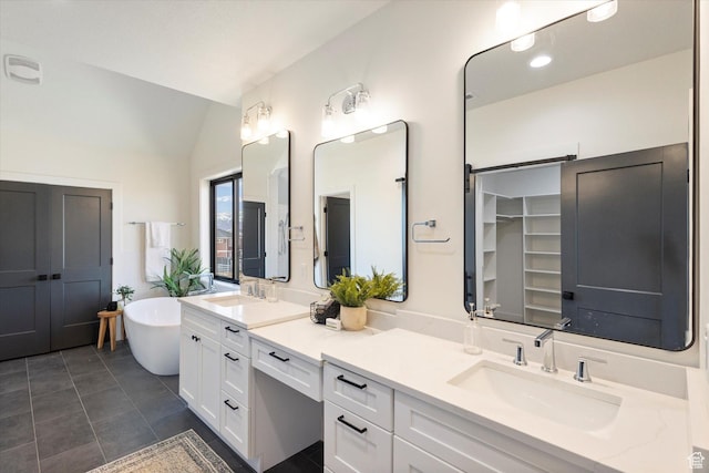 full bath featuring vaulted ceiling, a closet, a sink, a freestanding bath, and double vanity