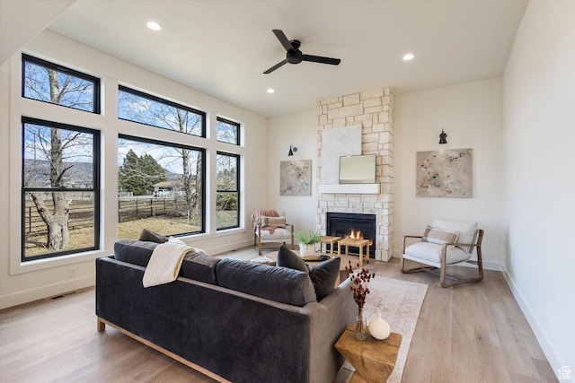 living room with baseboards, visible vents, ceiling fan, and light wood-type flooring