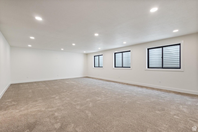 empty room with baseboards, recessed lighting, and light carpet