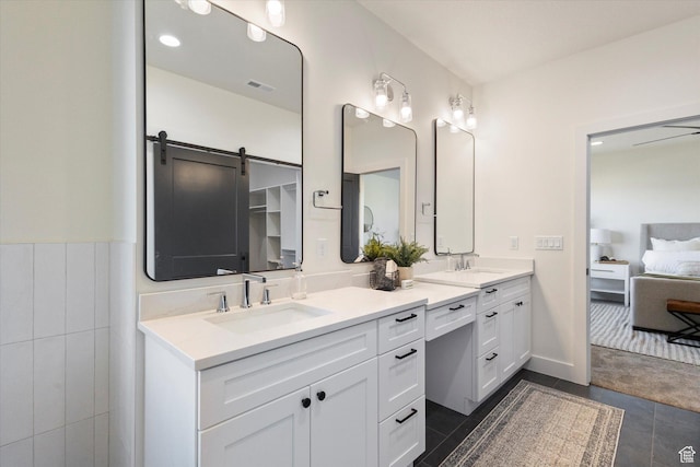 ensuite bathroom with double vanity, ensuite bath, a sink, and tile patterned floors