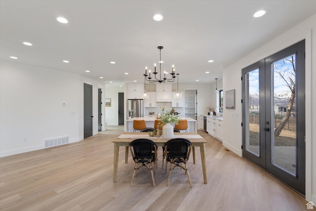 dining area featuring visible vents, a chandelier, light wood finished floors, recessed lighting, and french doors